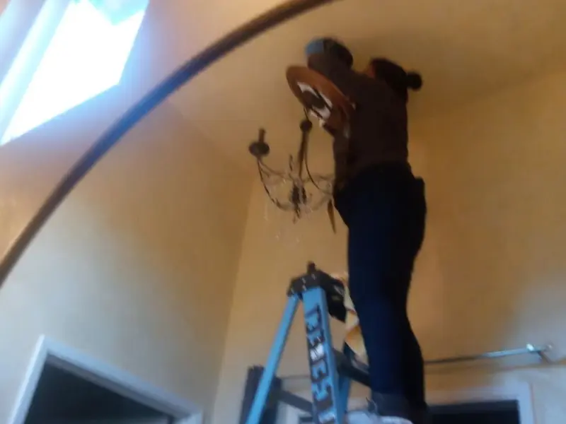 Electrician installing a chandelier in a Monson residence